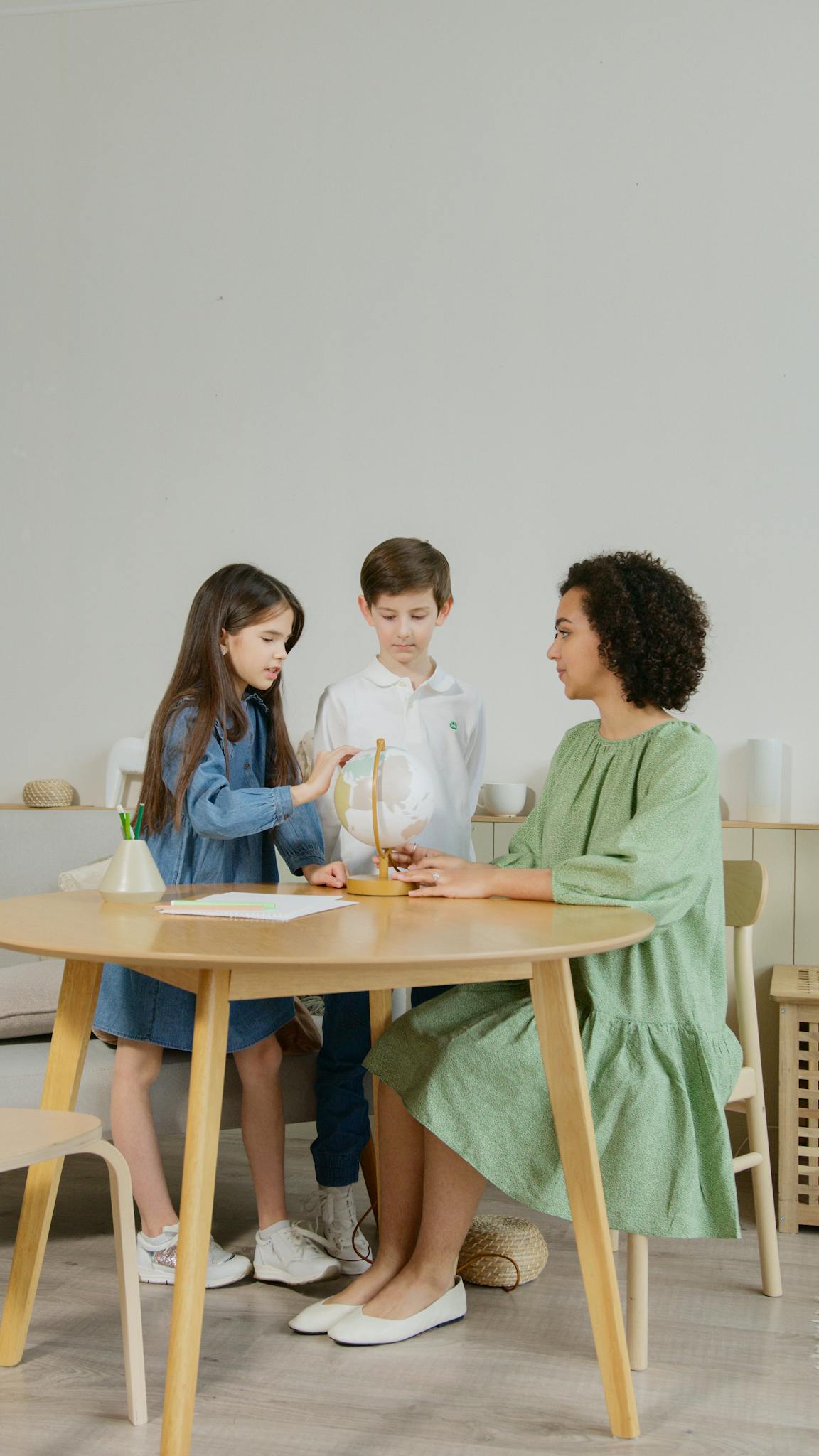A teacher and two children engage in a hands-on science activity indoors.